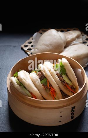 Concept alimentaire Buns Bao de bœuf bio ou Gua Bao dans plateau de ruisseau de bambou sur fond noir avec espace de copie Banque D'Images