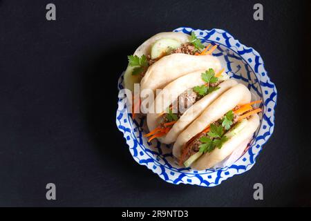 Concept alimentaire Buns Bao au bœuf bio ou Gua Bao dans une plaque en céramique asiatique sur fond noir avec espace copie Banque D'Images