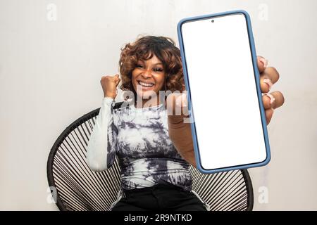 femme africaine excitée montrant un grand écran de téléphone Banque D'Images