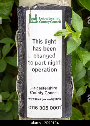 Un panneau sur une lampe de rue sur les heures d'éclairage de nuit restreintes pour économiser de l'énergie à Quorn, Leicestershire, Royaume-Uni. Banque D'Images