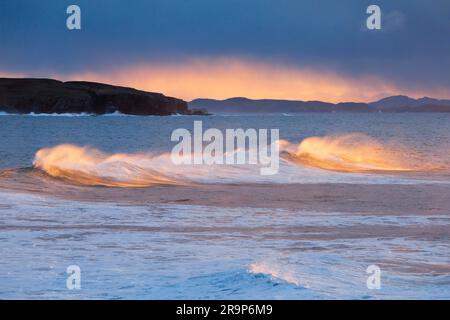 Grandes vagues s'écrasant pendant une tempête d'hiver, le jet tourbillonnant illuminé par la lumière chaude du soleil du soir. En arrière-plan, Summer Isles, près de Reiff, sur la côte nord-ouest de l'Écosse. Banque D'Images