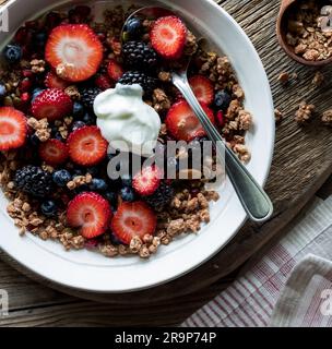 Un bol à petit-déjeuner composé de baies et de céréales, garni de yaourt grec. Banque D'Images