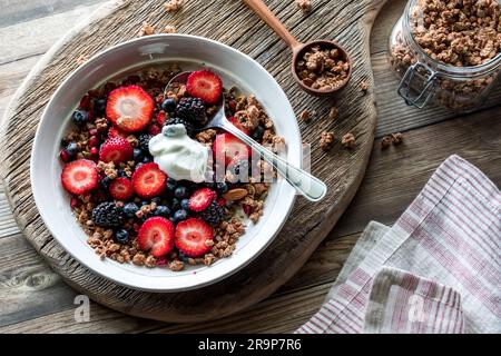 Un bol à petit-déjeuner composé de baies et de céréales et garni de yaourt grec. Banque D'Images