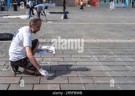 Kaiserslautern, Allemagne. 28th juin 2023. Artiste serbe Milivoj Koscic dans les premières étapes du processus de peinture. Onze artistes internationaux de 6 pays transforment le pavé Stiftsplatz (place) en art tridimensionnel. 3D l'art de la rue utilise la perspective pour créer l'illusion optique de l'espace. Les visiteurs sont invités à observer tous les artistes au travail pendant trois jours, du mercredi à 8 h 00 au vendredi à 6 h 00. Cette année, le sujet est « Digitalisation et Smart City ». Les tableaux illustrent des robots, des données ou des scénarios de cyberpunk. Credit: Gustav Zygmund/Alamy News Banque D'Images