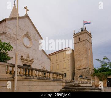 L'église paroissiale de l'Annonciation datant du 17th siècle et clocher de Supetar, île de Brac, Croatie. Sur la droite, la tour de l'horloge Leroj Banque D'Images