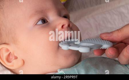 Un bébé garçon joue avec un anneau de dentition pendant l'éruption des premières dents. Démangeaisons et douleurs dans les gencives aux premières dents. Banque D'Images