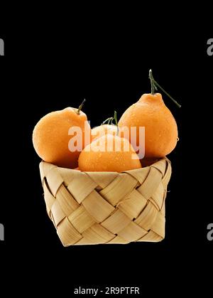 Un panier rempli d'oranges fraîches sur fond noir Banque D'Images