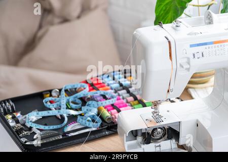 Disposition de couture avec bobines multicolores de fil de gros plan, aiguilles, machine à coudre électrique. Remplir le fil dans l'aiguille à coudre, en réglant le Banque D'Images