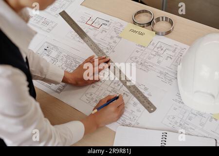 Vue de dessus d'une femme ingénieur qui dessine des plans et des plans sur un poste de travail dans un bureau, espace de copie Banque D'Images