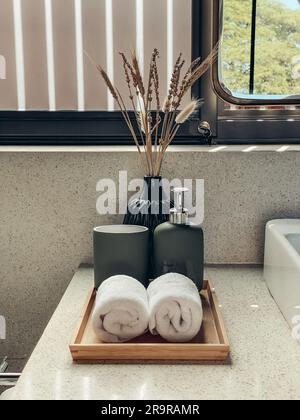 Deux essuie-mains dans la salle de bains avec distributeur de savon liquide sur un plateau en bambou Banque D'Images