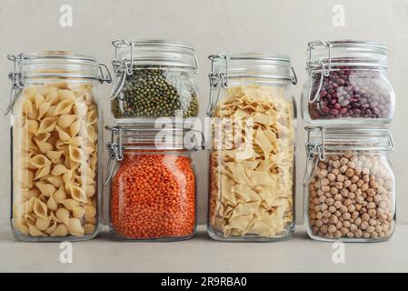 Haricots mung, haricots, pois chiches, lentilles rouges et deux types de pâtes dans des pots en verre. Concept de stockage des déchets zéro. Banque D'Images