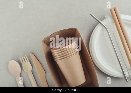 Ensemble de vaisselle écologique et d'emballages en papier kraft sur fond de béton léger. Emballage en papier pour aliments de rue - tasses, assiettes, pailles, contiennent Banque D'Images