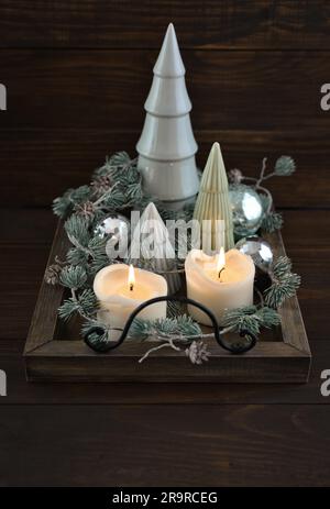Sapin en céramique décoratif avec boules de noël bleues et bougies sur plateau en bois sur fond de bois sombre Banque D'Images