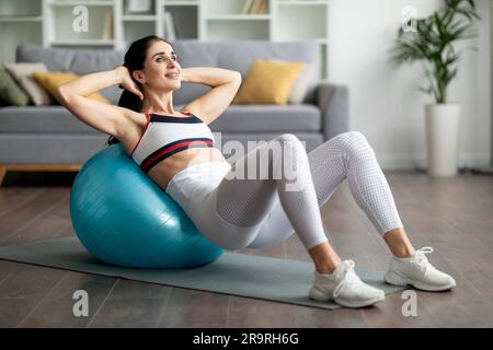 Jeune femme athlétique faisant des exercices avec le ballon de mise en forme à la maison Banque D'Images
