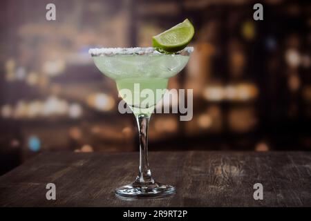 Cocktail de Margarita avec rondelles et limes entières sur une table de bar en bois. Ambiance de fête mexicaine Banque D'Images