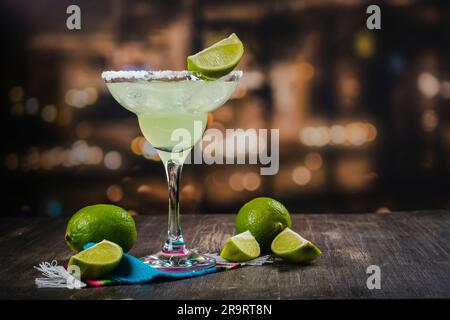 Cocktail de Margarita avec rondelles et limes entières sur une table de bar en bois. Ambiance de fête mexicaine Banque D'Images
