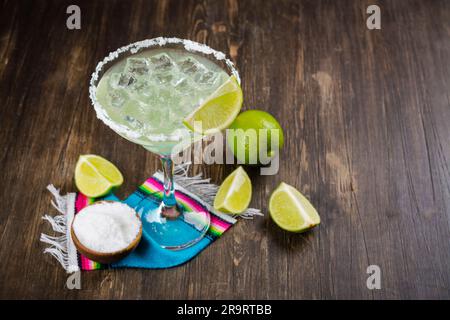 Cocktail de Margarita avec rondelles et limes entières sur une table de bar en bois. Ambiance de fête mexicaine Banque D'Images