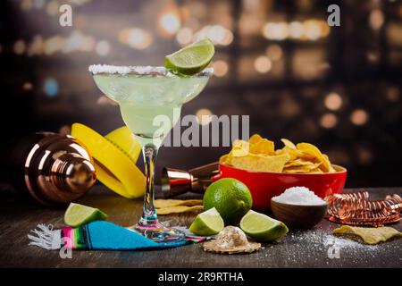 Cocktail de Margarita avec rondelles et limes entières sur une table de bar en bois. Ambiance de fête mexicaine Banque D'Images