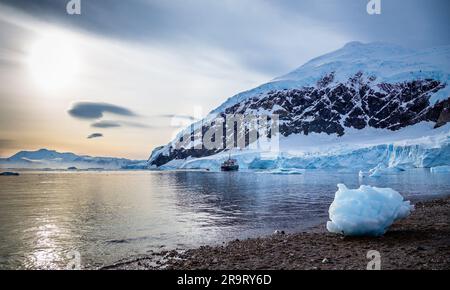 Grande partie bleue de l'iceberg sur la rive avec lagon et glacier en arrière-plan, baie de Neco, péninsule antarctique, Antarctique Banque D'Images