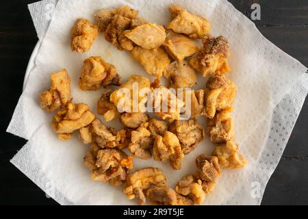 Gros plan de morceaux de poulet frits égoutter sur des serviettes en papier : nuggets de cuisse de poulet frits en morceaux sur une assiette recouverte d'une serviette en papier Banque D'Images