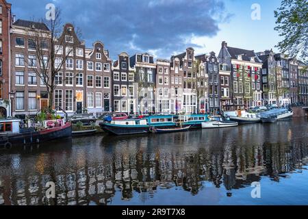 Maisons sur le canal Singel ainsi que des bateaux à moteur à Amsterdam Banque D'Images