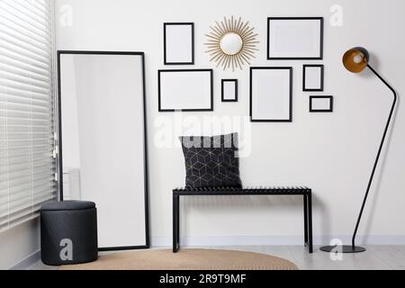 Intérieur élégant avec cadres vides suspendus sur un mur blanc et mobilier confortable Banque D'Images