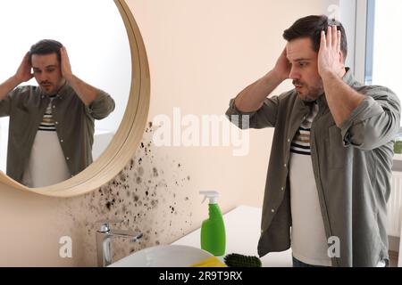 Homme choqué regardant affecté avec des murs de moisissure dans la salle de bains Banque D'Images