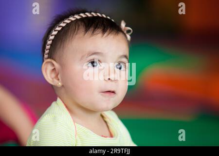 Portrait d'une belle fille de dix mois heureuse sur un fond coloré. Concept de stimulation précoce pour les tout-petits. Banque D'Images