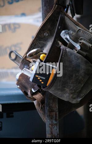 ceinture à outils bien utilisée accrochée sur le chantier, pleine d'outils, détecteur de goujons, clé, mètre à ruban, couteau, tournevis, pince Banque D'Images