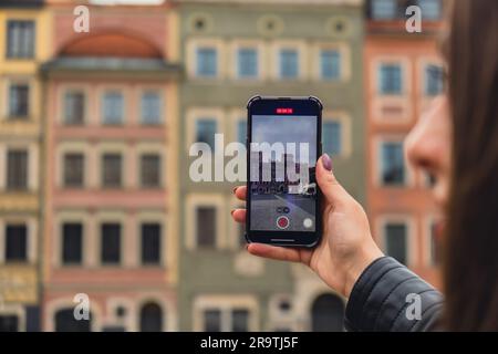 Une femme voyageur dans des lieux historiques regarde autour de la cour d'un monument et tourne de courtes vidéos par téléphone à Varsovie en Pologne. Photos touristiques lieu historique le jour ensoleillé. Femme méconnaissable Tourisme et blogging partage en ligne pour le public Voyage ensemble enregistrement vidéo sur téléphone mobile Banque D'Images