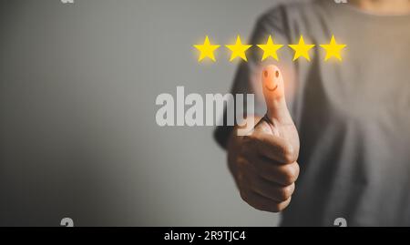 Main avec le pouce vers le haut l'icône de visage d'émotion positive et 5 étoiles avec espace de copie. Sourires émotionnels montrant une excellente satisfaction. note très im Banque D'Images