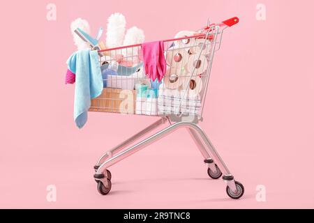 Chariot plein de produits de nettoyage sur fond rose Banque D'Images