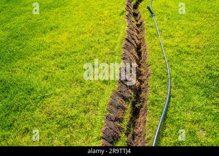 Auto-installation de l'irrigation avec un arroseur rétractable dans la pelouse finie. Pose de conduites d'eau avec des pulvérisateurs sous la pelouse pour l'irrigation. Banque D'Images