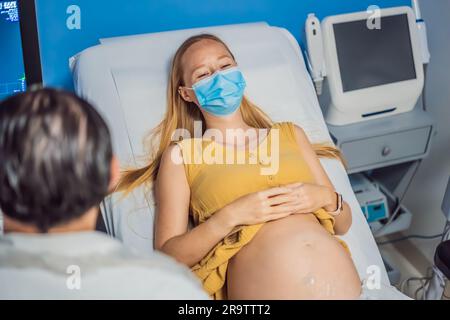 À l'hôpital, la prise de vue rapprochée du médecin effectue une procédure d'échographie à une femme enceinte. Capteur de mouvement obstétricien sur le ventre de Banque D'Images