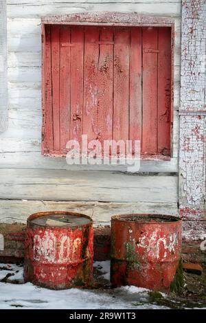 Arrière-plan ancien et abandonné. Mur en bois avec peinture écaillée et fûts rouillés. Banque D'Images