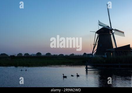 De magnifiques moulins à vent en bois au coucher du soleil dans le village hollandais de Kinderdijk. Les moulins à vent courent sur le vent. Les beaux canaux hollandais sont remplis d'eau. Banque D'Images