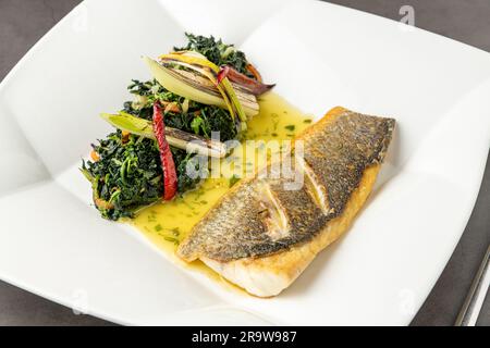 Filet de bar grillé servi avec des garnitures dans un restaurant gastronomique Banque D'Images