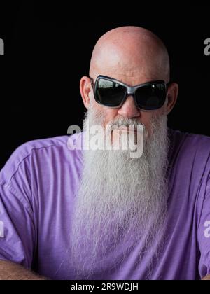 Portrait d'un homme avec une longue barbe grise portant un t-shirt violet et des lunettes de soleil gros plan Banque D'Images