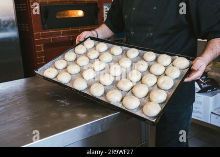 Boulanger méconnaissable avec un plateau de pains crus savoureux. Cuisine italienne traditionnelle Banque D'Images