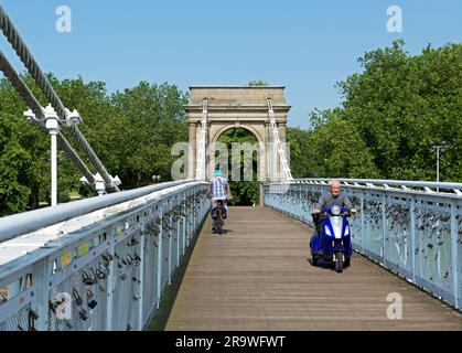 Cycliste et homme en scooter de mobilité traversant la passerelle Wilford, enjambant la rivière Trent, Nottingham, Notinghamshire, East Midlands, Angleterre Banque D'Images