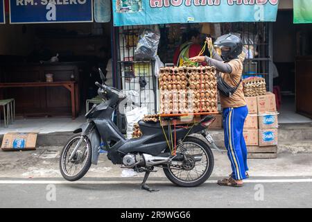 Jakarta, Indonésie - 29 mai 2023: Un homme non identifié empilant de petites palettes d'œufs sur une moto. Banque D'Images