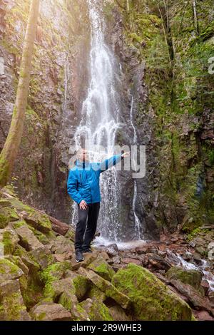 Tourist attraction of Germany - falls of Burgbach Waterfall near Schapbach, Black Forest, Baden-Wurttemberg, Germany. Man hiker in blue jacket Banque D'Images