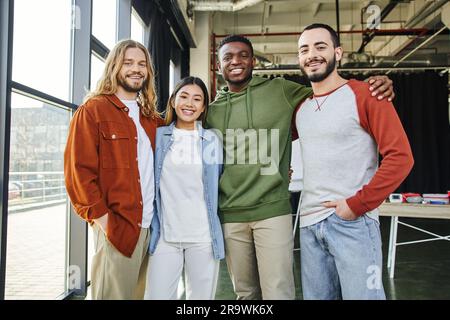 homme afro-américain embrassant des amis interraciaux débordés dans des vêtements élégants et décontractés regardant l'appareil photo dans un bureau moderne, divers collègues d'affaires d'équipe Banque D'Images