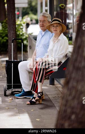 Un couple plus âgé vêtu de vêtements d'été avec un chariot attendant un bus à un arrêt de bus, Cologne, Rhénanie-du-Nord-Westphalie, Allemagne Banque D'Images