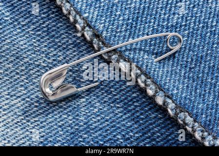 Goupilles de sécurité fermé sur un tissu denim bleu jeans Banque D'Images