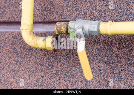 Un tube à gaz jaune cassé, avec un robinet, à l'extérieur d'une maison pour canaliser l'énergie douce à la maison Banque D'Images