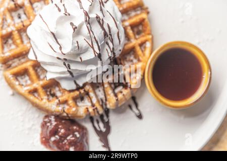 Une image en gros plan d'une délicieuse gaufre recouverte de crème fouettée crémeuse et de sirop de chocolat Banque D'Images