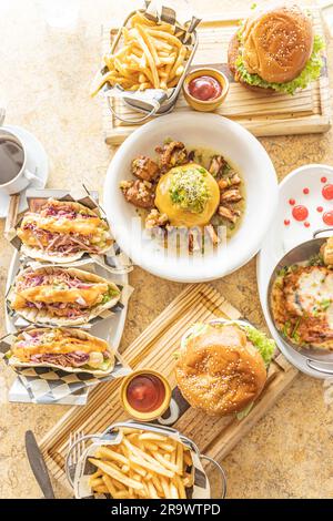 Une vue de haut en bas d'une table en marbre recouverte d'une sélection de plats délicieux comprenant des hamburgers, des frites, des tacos et des salades Banque D'Images