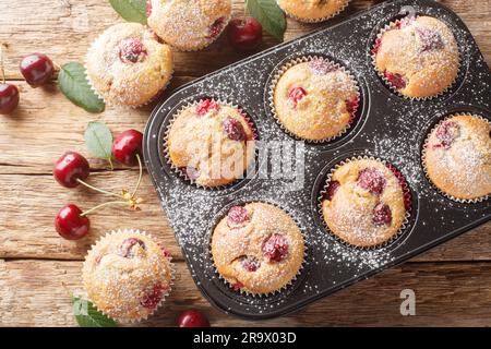 Muffins maison doux et aigre avec cerises fraîches dans un moule à muffins sur la table. Vue horizontale du dessus Banque D'Images