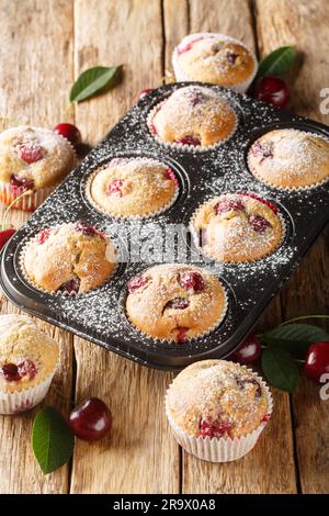 Muffins aux cerises faits maison dans des sous-gâteaux et cerises fraîches en gros plan. Verticale Banque D'Images
